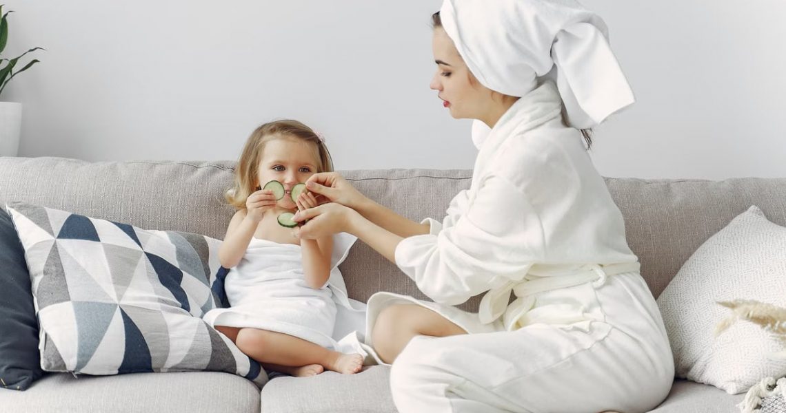 A mother and daughter enjoy a spa day at home, bonding on the couch with cucumber slices.